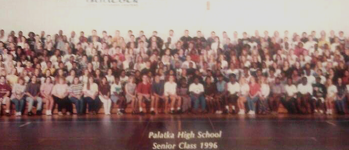 Palatka High School class of 1996 photo sitting in the gym on bleachers.